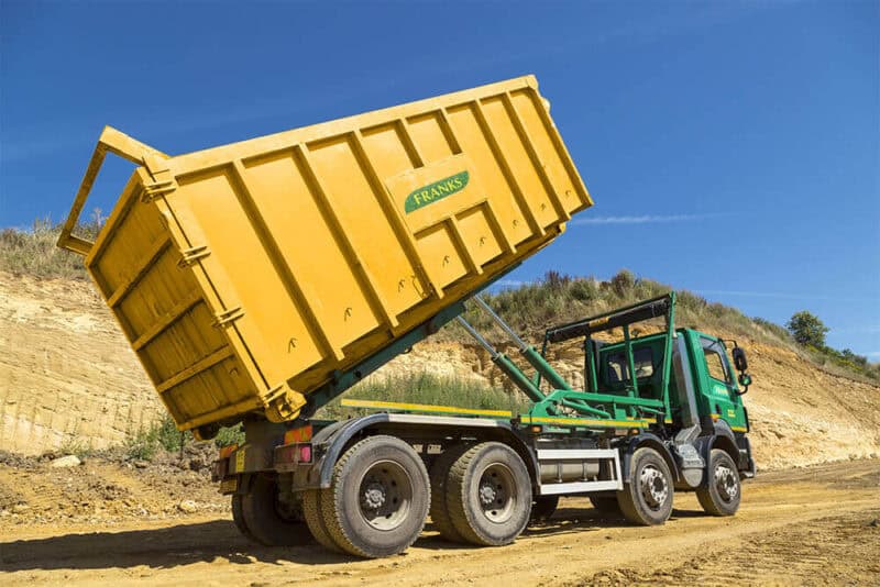 J&J Franks branded RORO vehicle with the bed lifted in a sandy quarry.